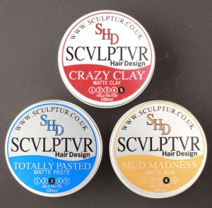 Pic of Mens Hair Wax Tins – called Crazy Clay, Totally Pasted and Mud Madness – designed for Sculptur Hair, Glasgow by Adamson Design. The lower half of the round silver tins are printed Red for Crazy Clay, Royal Blue for Totally Pasted and Yellow Ochre for Mud Madness in a soft wave shape.